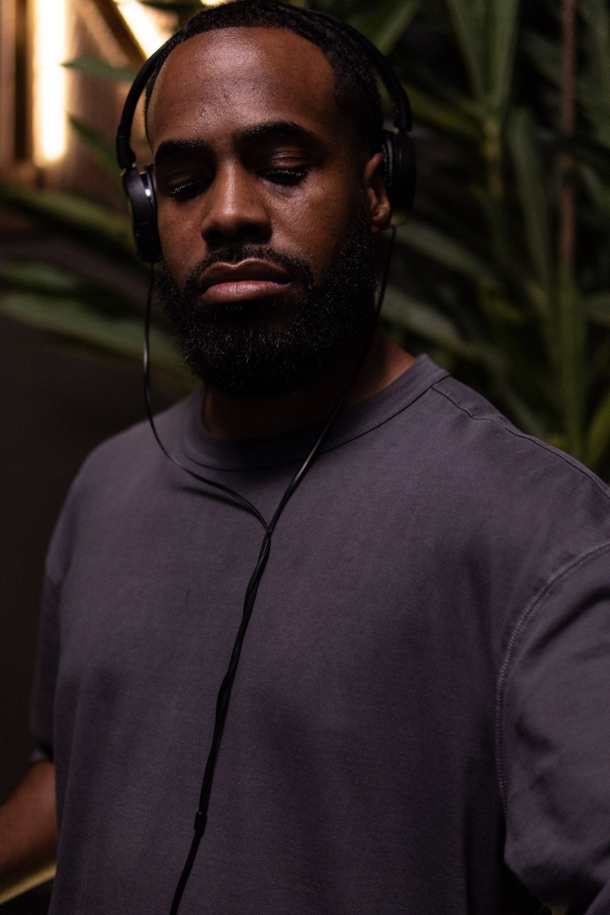 DJ wearing headphones with eyes closed in a dimly lit venue