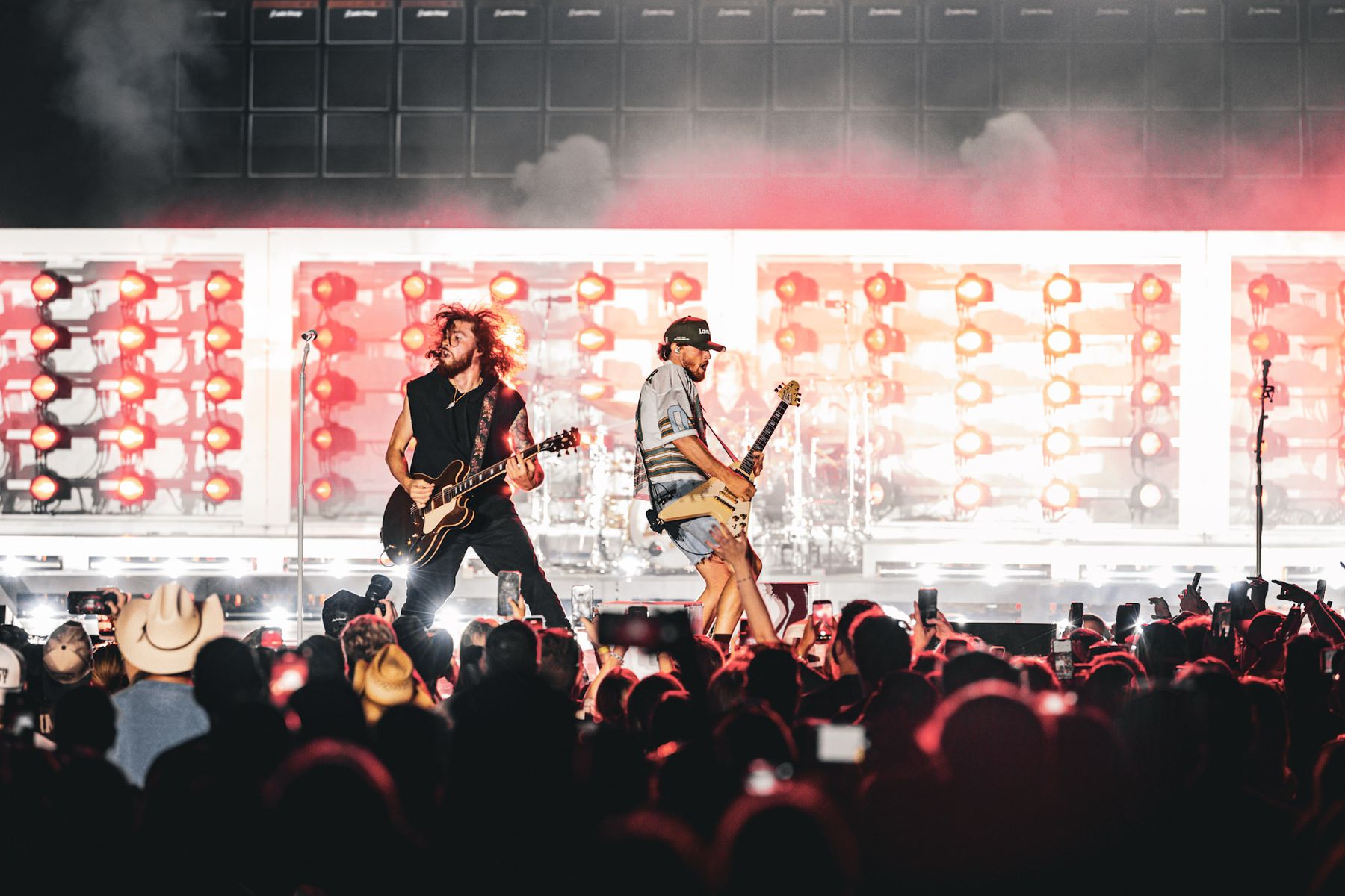 Guitarists performing on a lit stage in front of a crowd