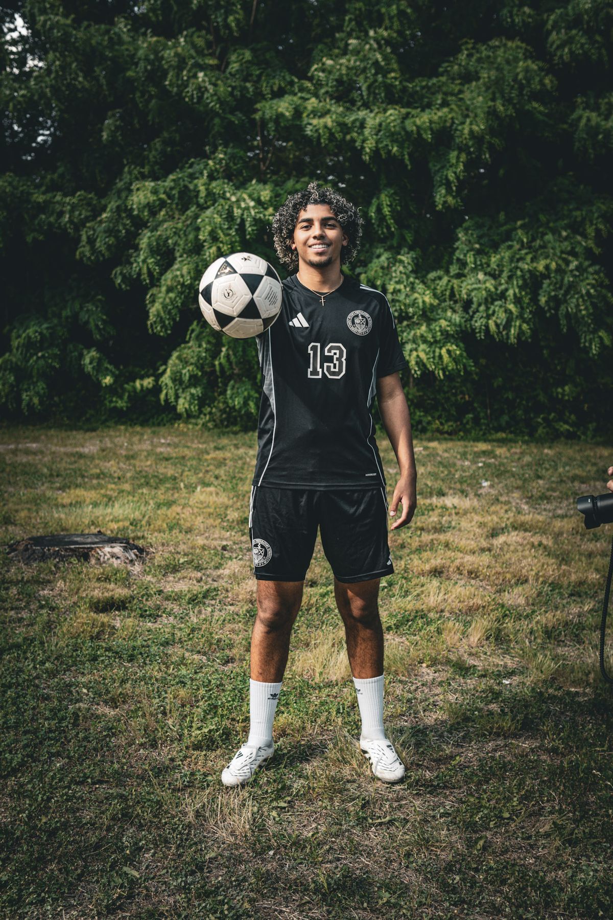 Soccer player in a black number 13 jersey holding a ball outdoors